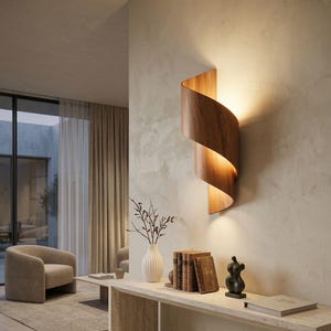 May include: A contemporary wooden wall light with a spiral design, casting a warm glow. The fixture is mounted on a neutral wall, enhancing the minimalist interior. The room features a neutral colour palette with a sofa, rug, and decorative items.