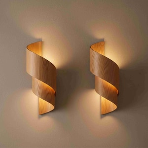 Könnte beinhalten: Zwei Wandleuchten aus Holz mit einem spiralförmigen Design. Die Leuchten sind aus hellfarbigem Holz gefertigt und strahlen ein warmes, einladendes Licht aus. Das Design ist modern und elegant, geeignet für die Innenbeleuchtung.