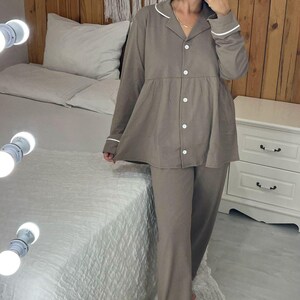 Peut inclure: Ensemble de pyjama deux pi&egrave;ces marron clair. Le haut est boutonn&eacute; avec une bordure blanche sur le col et les poignets. Le pantalon assorti est ample. L'ensemble est fait d'une mati&egrave;re douce et confortable.