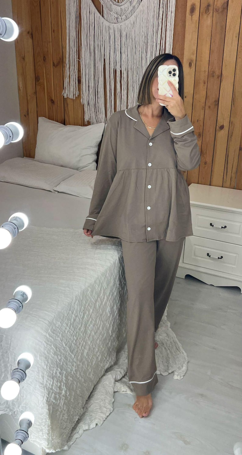 Peut inclure: Ensemble de pyjama deux pi&egrave;ces marron clair. Le haut est boutonn&eacute; avec une bordure blanche sur le col et les poignets. Le pantalon assorti est ample. L'ensemble est fait d'une mati&egrave;re douce et confortable.