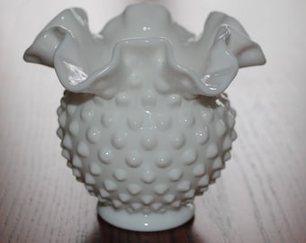 May include: White milk glass vase with a ruffled top and a textured, bumpy surface. The vase is round and has a small base.