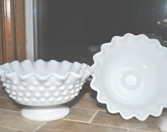 May include: Two white milk glass bowls with a scalloped edge and a raised dot pattern. The bowls are on a tiled surface.