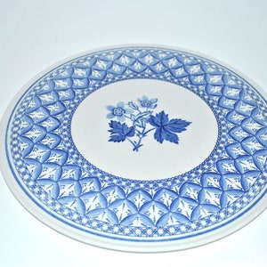 May include: A white ceramic plate with a blue and white floral design. The plate has a decorative border with a geometric pattern.
