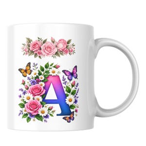 May include: A white ceramic mug featuring a gradient blue and pink letter A surrounded by pink roses, white daisies, and purple lavender. Two colourful butterflies are perched near the floral arrangement, with a separate rose bouquet above.