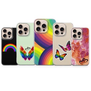 Könnte beinhalten: Eine Sammlung von fünf Handyhüllen mit verschiedenen Designs. Eine Hülle zeigt einen Regenbogen, eine andere hat bunte Flügel, eine dritte zeigt ein Regenbogenmuster und die vierte zeigt zwei Schmetterlingsaufkleber. Die letzte Hülle hat ein rosa-oranges Marmormuster.