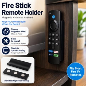 May include: A black magnetic remote holder for Fire TV remotes, featuring a curved cradle and a magnetic backing piece. The holder is shown mounted on a dark wood surface, with text labels describing it as magnetic, minimal, and secure.