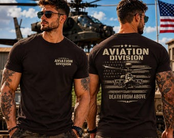 May include: A black short-sleeved t-shirt featuring a small graphic on the front chest that reads AVIATION DIVISION with three stars. The back displays a large graphic of a military helicopter over an American flag with the text AVIATION DIVISION and DEATH FROM ABOVE.