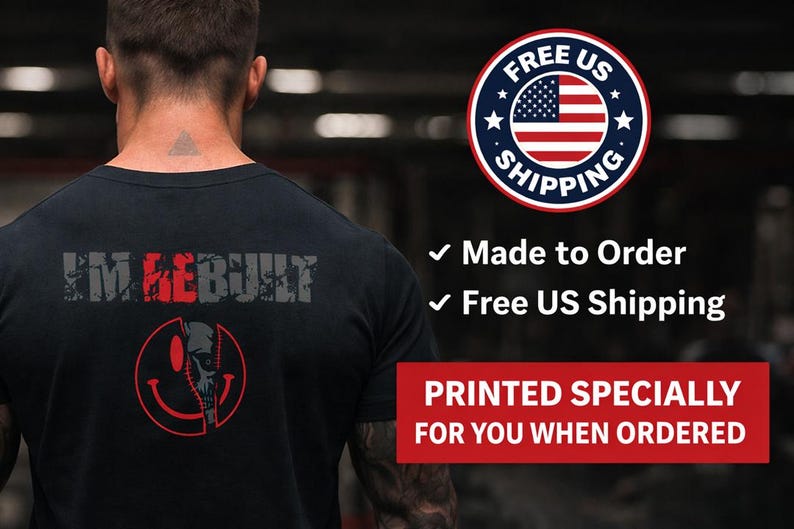 Puede incluir: Una camiseta negra con el texto I'M REBUILT en letras grises y rojas desgastadas en la parte posterior. Debajo del texto hay un gr&aacute;fico rojo de una cara sonriente dividida con un dise&ntilde;o de calavera. La camiseta se muestra desde atr&aacute;s.