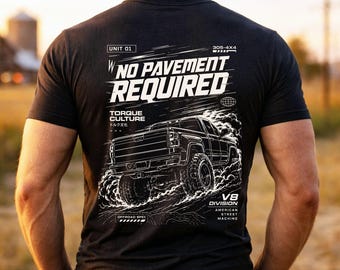 May include: Dark gray t-shirt with a white graphic of a truck and the text "NO PAVEMENT REQUIRED." Additional text includes "TORQUE CULTURE," "V8 DIVISION," and "AMERICAN STREET MACHINE."