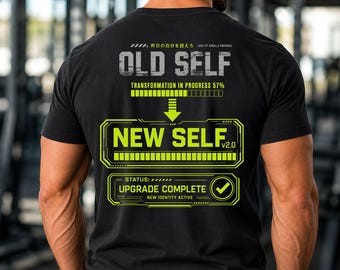 May include: A black short-sleeve t-shirt featuring a graphic on the back with the text OLD SELF, TRANSFORMATION IN PROGRESS 57%, NEW SELF v2.0, and STATUS: UPGRADE COMPLETE. The design includes progress bars, a downward arrow, and a checkmark.