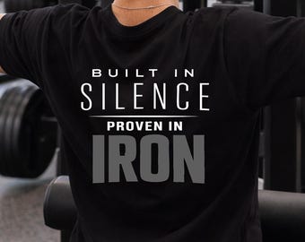 May include: Black t-shirt with the text "BUILT IN SILENCE PROVEN IN IRON" in white and gray lettering. The shirt is made of a soft material and is suitable for workouts.