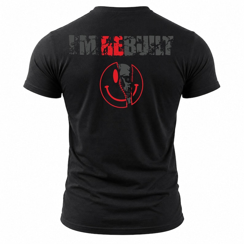 Puede incluir: Una camiseta negra de manga corta con el texto I'M REBUILT en letras grises y rojas desgastadas. Debajo del texto hay un gr&aacute;fico de una cara sonriente circular roja con una costura vertical en el centro que revela un dise&ntilde;o de calavera.