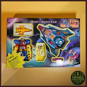 Può includere: Un set di gioco Space Attack Unit Star World da 12 pezzi in una scatola rettangolare. Il set include un aereo giocattolo giallo, un robot rosso, blu e giallo con scudo e un'astronave blu e viola. La scatola presenta grafiche a tema spaziale.