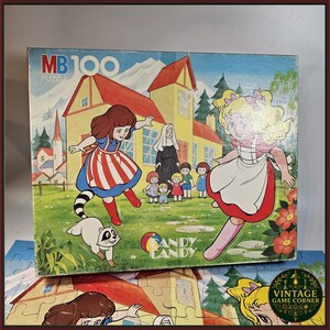 May include: Vintage MB 100 Candy Candy puzzle box featuring cartoon illustrations of girls, a raccoon, and a house. The box has a colorful design with the words "Candy Candy" on it. The puzzle is a vintage item.