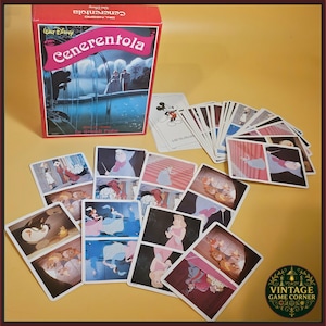 May include: A Walt Disney Cenerentola card game set featuring a red box with a Cinderella illustration and the title Cenerentola. The set includes a deck of playing cards with various scenes from the film, including characters like Cinderella, the Fairy Godmother, and mice, displayed in a fan and scattered arrangement.