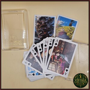 May include: A deck of playing cards featuring illustrations from a movie, with a clear plastic case. The cards are fanned out, displaying various suits and face cards. The Joker cards show a large, detailed image. The case has the text "STUDIO GHIBLI".