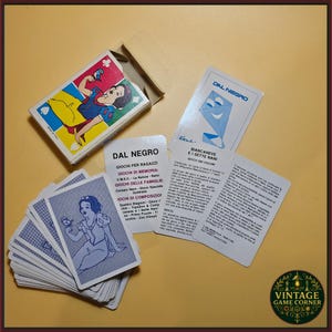 Può includere: Un mazzo di carte da gioco Dal Negro raffigurante Biancaneve, comprensivo di scatola in cartone, una carta con retro blu e illustrazione di un aquilone, e carte istruzioni con testo nero in italiano che descrivono le regole del gioco.