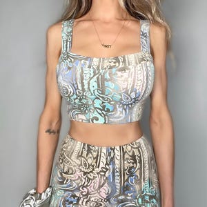 May include: A two-piece outfit with a blue, white, and brown paisley print. The top is a cropped tank top with a square neckline. The bottom is a skirt with a high waist.