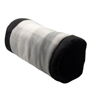 May include: A cylindrical pet bed with a black and white plaid pattern. The ends of the bed are black. The bed is made of a soft, plush material.