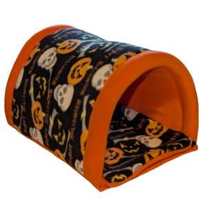 Może przedstawiać: Tunel dla zwierząt domowych o tematyce Halloween w kolorze pomarańczowym i czarnym. Tunel ma czarną tkaninę z pomarańczowymi dyniami i białymi czaszkami. Krawędzie są wykończone w jasnym pomarańczu. Na tkaninie wydrukowano napis "Happy Halloween".