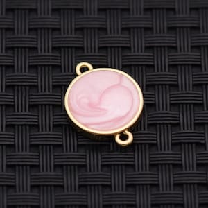 May include: A gold-colored, round jewelry finding with a pink, swirled enamel center. The finding has two loops for attaching to other jewelry components. The design is simple and elegant, suitable for various jewelry projects.