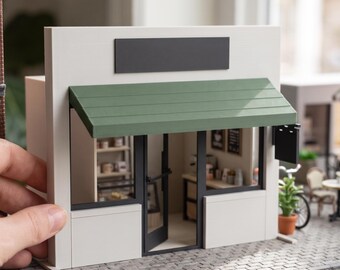 May include: A miniature model of a storefront with white walls, a dark green awning, and a black door. The text reads DIGITAL STL FILES - NO PHYSICAL ITEM and INSTANT DOWNLOAD. The model features a visible interior with shelves and a counter.