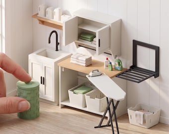 May include: Digital STL files for a miniature laundry room set including a white sink cabinet, wall cabinet, wooden countertop, ironing board, wall-mounted drying rack, storage baskets, and a green textured laundry hamper. Text reads: DIGITAL STL FILES - NO PHYSICAL ITEM and INSTANT DOWNLOAD.