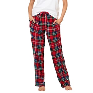 Può includere: Pantaloni da pigiama a quadri rossi con vita con coulisse. I pantaloni presentano un classico motivo a quadri in rosso, verde e blu. La modella indossa una maglietta bianca. I pantaloni hanno tasche.