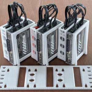 May include: Three white computer enclosures with black cables and connectors. The enclosures have a clear front panel, revealing internal components. A white mounting plate is in the foreground.