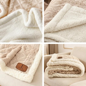 May include: A beige and white throw blanket featuring a textured cable knit pattern on one side and a soft white sherpa fleece lining on the reverse. A brown rectangular faux leather patch is stitched to the corner with the letter L and LEONA.