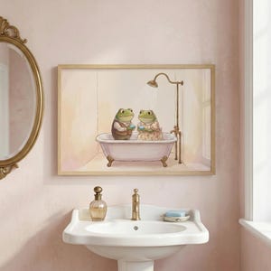 Peut inclure: Une impression encadrée représente deux grenouilles de dessin animé dans une baignoire sous une douche. Les grenouilles portent des vêtements et tiennent des débarbouillettes. La scène de la salle de bain a une esthétique vintage.