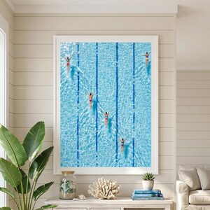 Könnte beinhalten: Ein gerahmter Kunstdruck mit einer Luftaufnahme eines Schwimmbeckens mit mehreren Schwimmern. Das Becken hat blaue Bahnen und das Wasser ist hellblau. Die Schwimmer tragen Badeanzüge und sind im Becken verteilt.