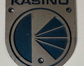 Insignia con el logotipo de Kasino Electronics (1973-1975) para amplificadores de guitarra o bajo.