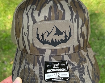 Mountain Antler Patch Richardson 112 Trucker Hat | Camo Hunting | Snapback Mesh Back Cap | Deer | Bottomland Camo | Leather | Mossy Oak