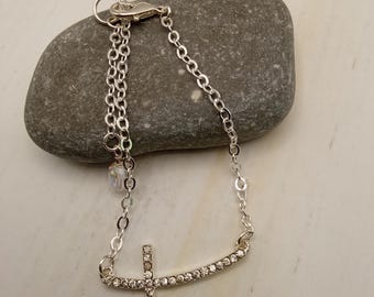 Pulsera con dije de cruz de plata de ley y detalles de pedrería.