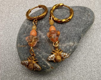 Brincos de argola dourados em formato de abelha com detalhes em strass.