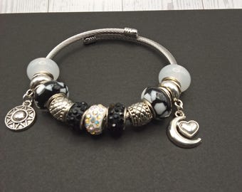 Pulseira rígida com contas boho de furo grande em preto/branco/prata e pingentes celestiais.