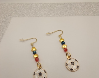 Brincos dourados com tema de futebol dos EUA, com pingentes patrióticos em esmalte e detalhes em vermelho, branco e azul.