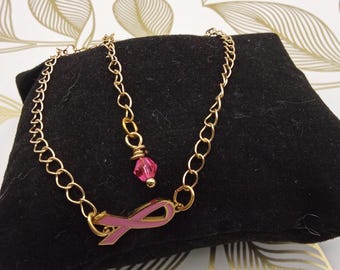 Pulsera con dije de cadena dorada para concienciar sobre el cáncer de mama y dije de esmalte rosa.