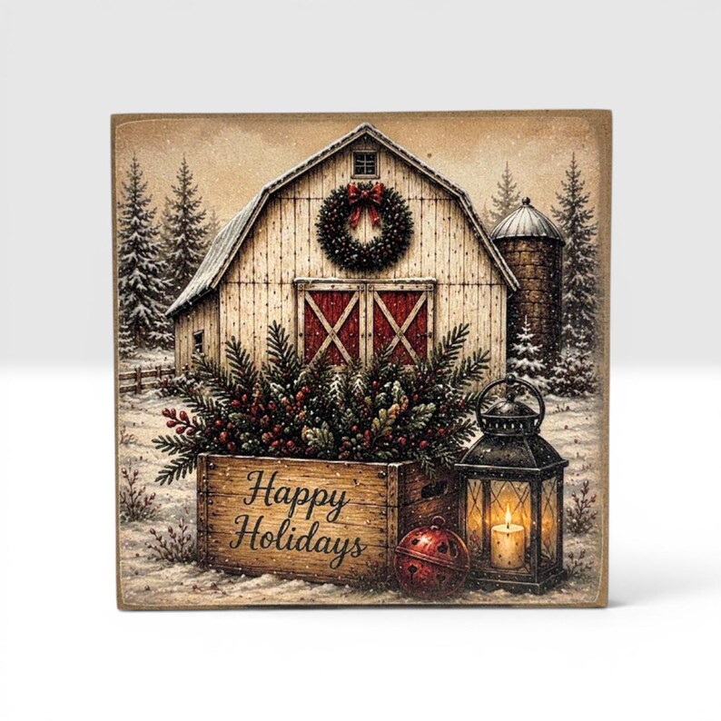 Puede incluir: Un letrero de madera cuadrado con una escena de granero invernal, una corona, una caja llena de ramas de pino y bayas, un cascabel rojo y un farol negro con una vela encendida. El texto Happy Holidays est&aacute; impreso en la parte frontal de la caja.