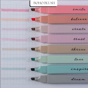 May include: A set of pastel highlighters with motivational words such as "smile" and "believe". The highlighters are displayed on grid paper, each leaving a coloured streak. The brand name "BOHO BLUSH" is visible at the top of the image.