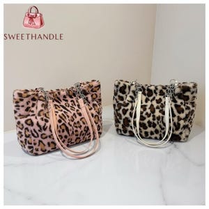 Puede incluir: Dos bolsos tote de piel sintética con estampados de leopardo. Un bolso es rosa y marrón, el otro es marrón y crema. Ambos bolsos tienen asas de cadena y correa. La marca "SWEETHANDLE" es visible en la esquina superior izquierda.