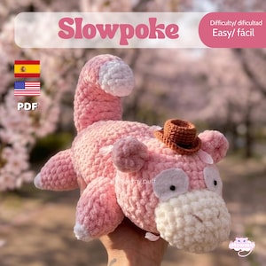 May include: A handmade pink Slowpoke plushie with a small brown hat. The plushie has white accents on its tail, ears, and face. The word "Slowpoke" is written in pink above the plushie. The difficulty level is "Easy".