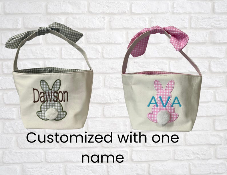 Peut inclure: Deux paniers de P&acirc;ques en toile avec des motifs de lapin. L'un a un n&oelig;ud et une doublure en vichy vert et blanc, avec le nom "Dawson" brod&eacute;. L'autre a un n&oelig;ud et une doublure en vichy rose et blanc, avec le nom "AVA" brod&eacute;.