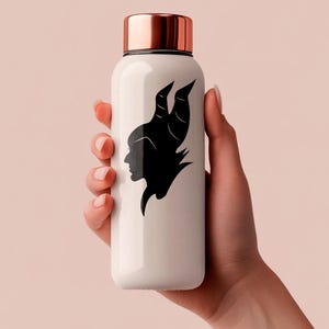 May include: A white water bottle with a copper-colored lid. The bottle features a black silhouette of a character with horns. The bottle is held by a hand against a light pink background.