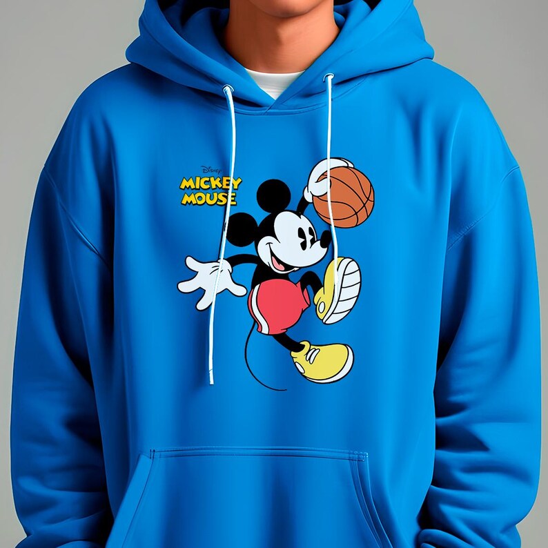 May include: A blue hooded sweatshirt featuring a graphic of Mickey Mouse playing basketball. The cartoon character is in motion, holding a basketball. The sweatshirt has a drawstring and a front pocket. The text "Disney MICKEY MOUSE" is printed on the front.