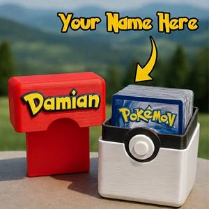 Op de afbeelding: Een rode en witte kaarthouder met de naam "Damian" in gele letters. De houder staat naast een witte en zwarte container in de vorm van een Poké Ball, gevuld met Pokémon-kaarten. Bovenin staat de tekst "Your Name Here".