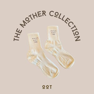 Puede incluir: Dos pares de calcetines color crema con el texto "MAMA'S QUIET TIME" impreso en el puño. Los calcetines tienen un patrón antideslizante en las suelas. La imagen también incluye el texto "THE MOTHER COLLECTION".