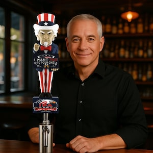May include: A beer tap handle featuring an Uncle Sam figure with a red, white, and blue color scheme. The handle has the text "I WANT YOU TO POUR ONE" and "USA 1776 Uncle Sam's IPA". The tap handle is made of metal.