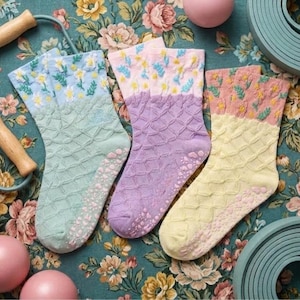 May include: Three pairs of colorful socks with floral patterns and textured soles. The socks are in shades of mint green, lavender, and yellow, with pink and yellow floral designs on the cuffs. A jump rope and exercise balls are also in the image.